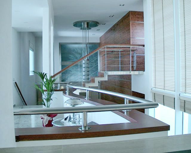 Detalle de un interior de vivienda con una baranda y una escalera con una elegante línea de diseño.