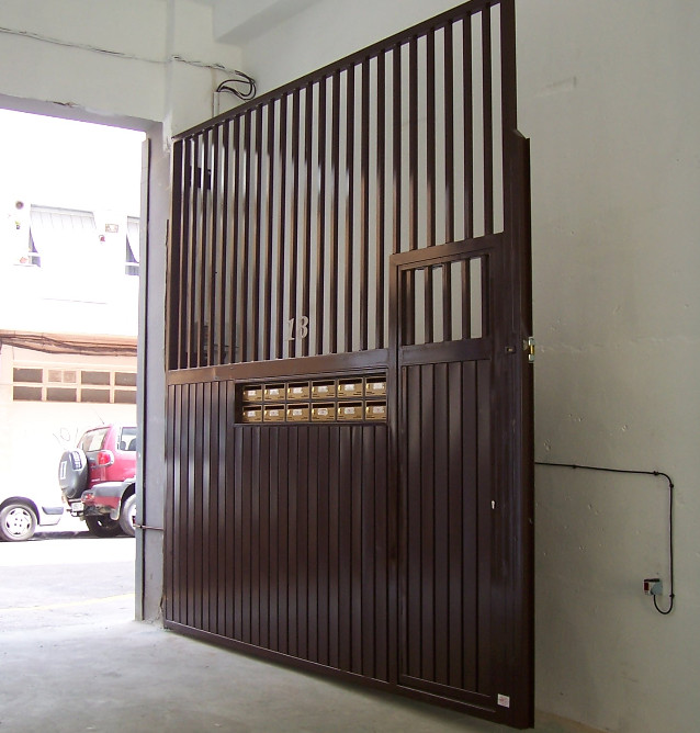 Puerta automatica para garaje de comunidad de barrotes y chapa laminada con buzones y peatonal inscrita