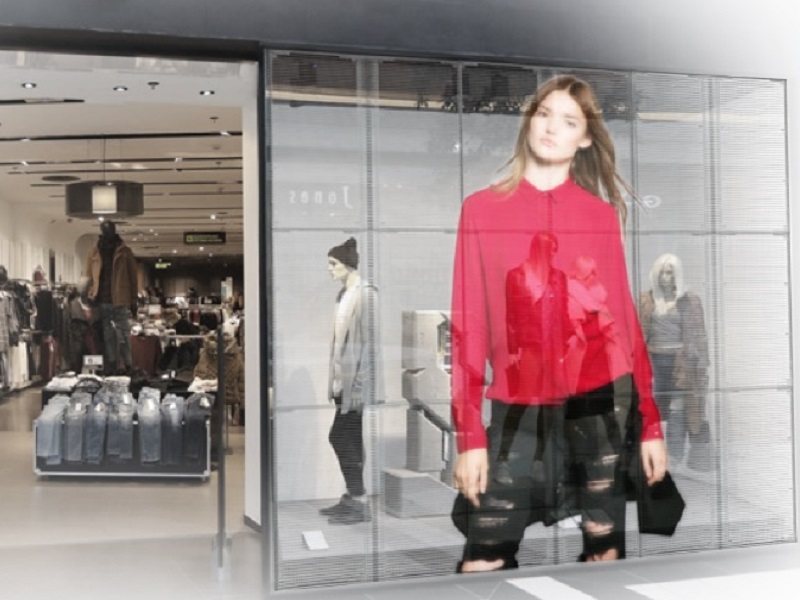 El escaparate de una tienda de ropa mostrando prendas en una pantalla semitransparente